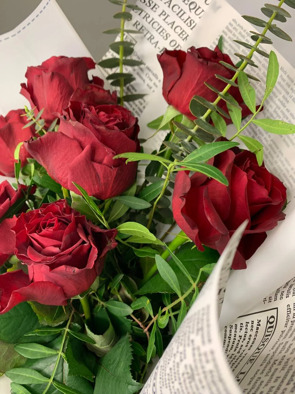 Bukiet czerwonych róż w oryginalnym papierze z gazetowym wzorem