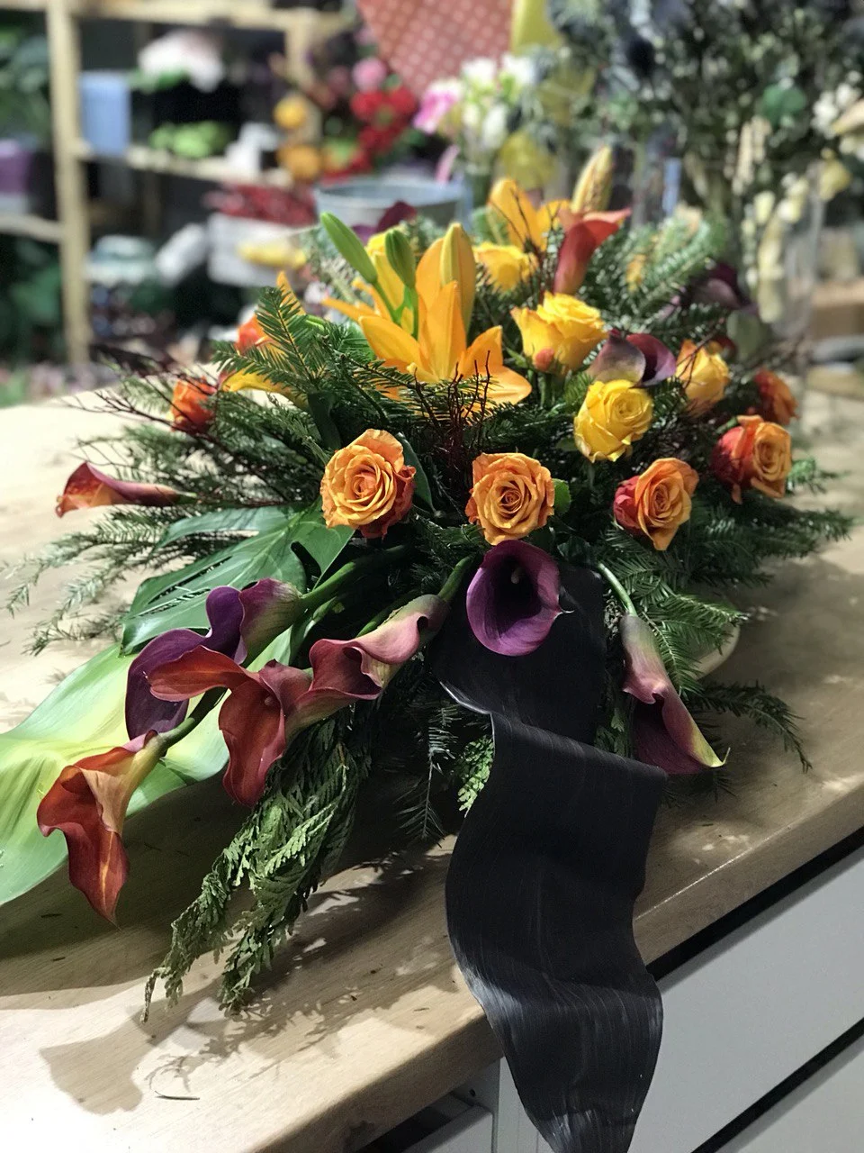 Kompozycja pogrzebowa z różami, liliami i gałązkami zieleni