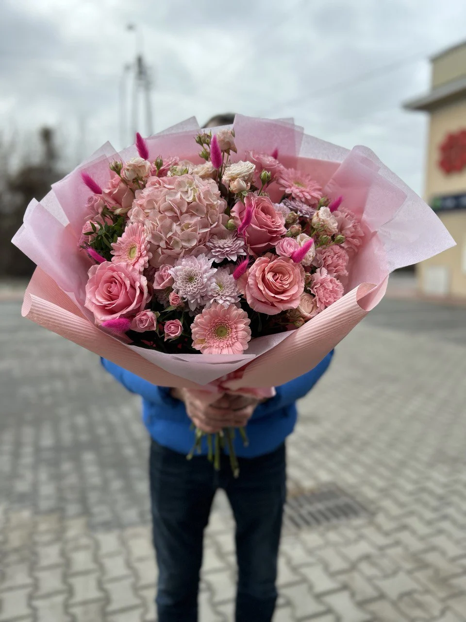 Bukiet różowych kwiatów z róż, hortensji i gerbery w pastelowym papierze