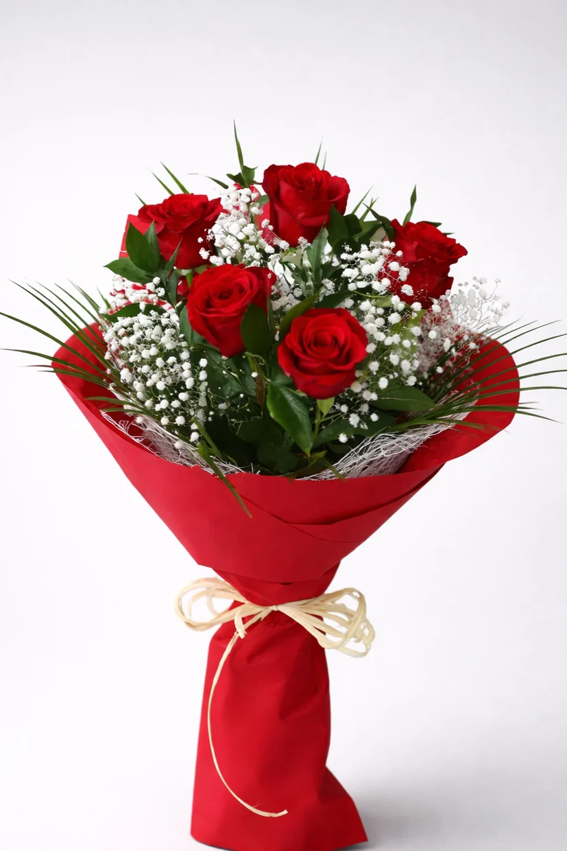Bukiet czerwonych róż z gipsówką w czerwonym papierze ozdobnym