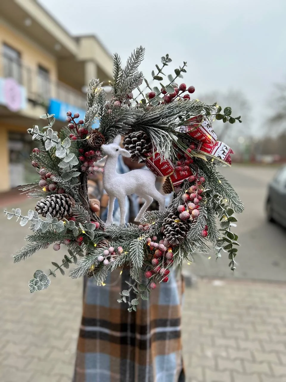 Zimowa dekoracja z szyszkami, jeleniem i czerwonymi akcentami – świąteczny wieniec na drzwi