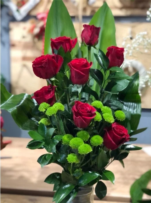 Bukiet z czerwonych róż i zielonych chryzantem w szklanym wazonie