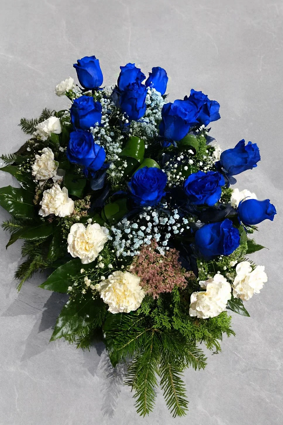 Wiązanka pogrzebowa z niebieskich róż i białych dodatków