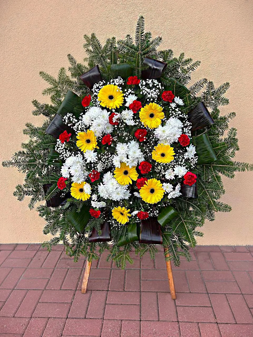 Elegancki wieniec pogrzebowy z gerberami i goździkami na stojaku